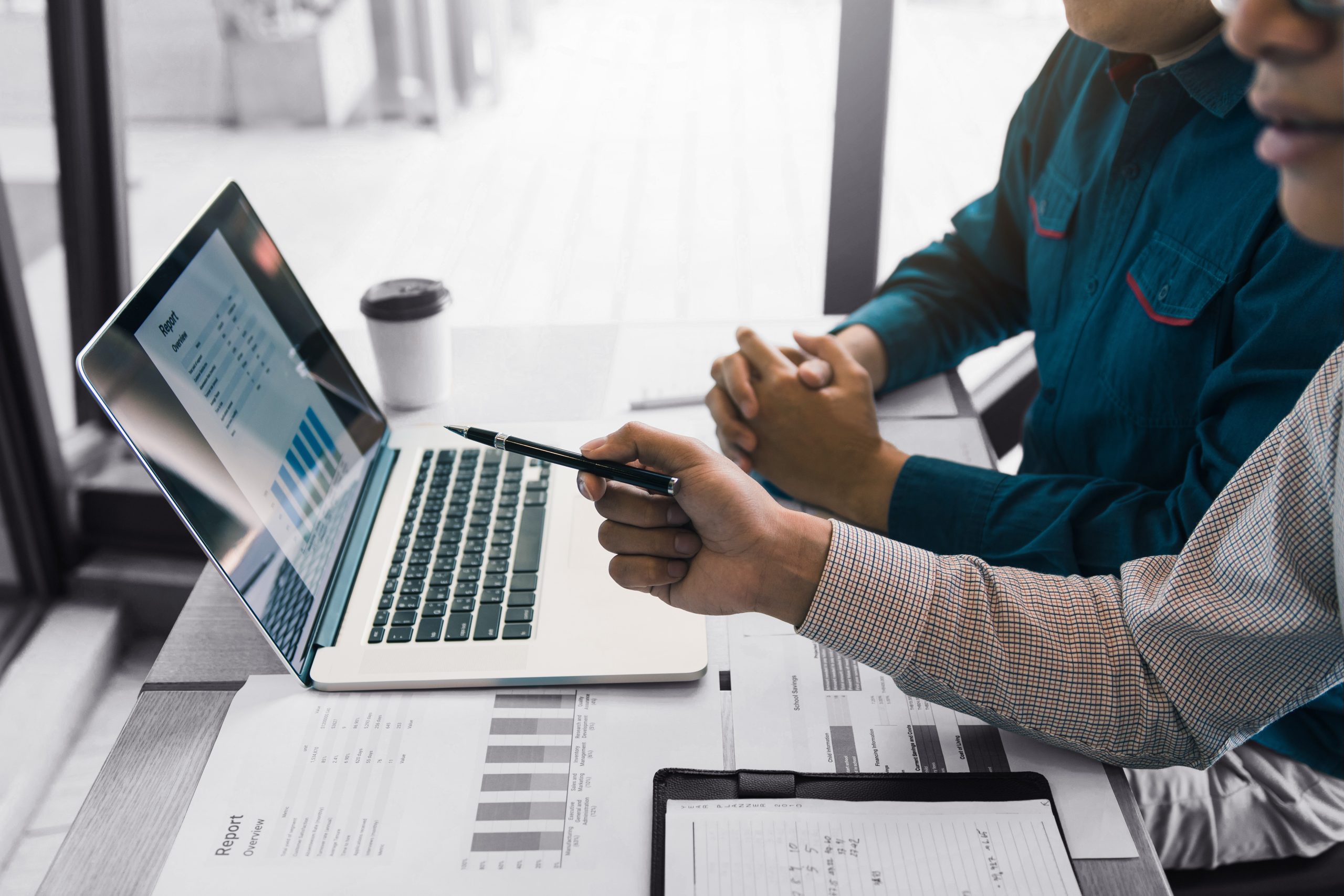 Business partnership pointing to the graph of the company financial statements report and profits earned during in the computer screen with giving a presentation to colleagues in office room.