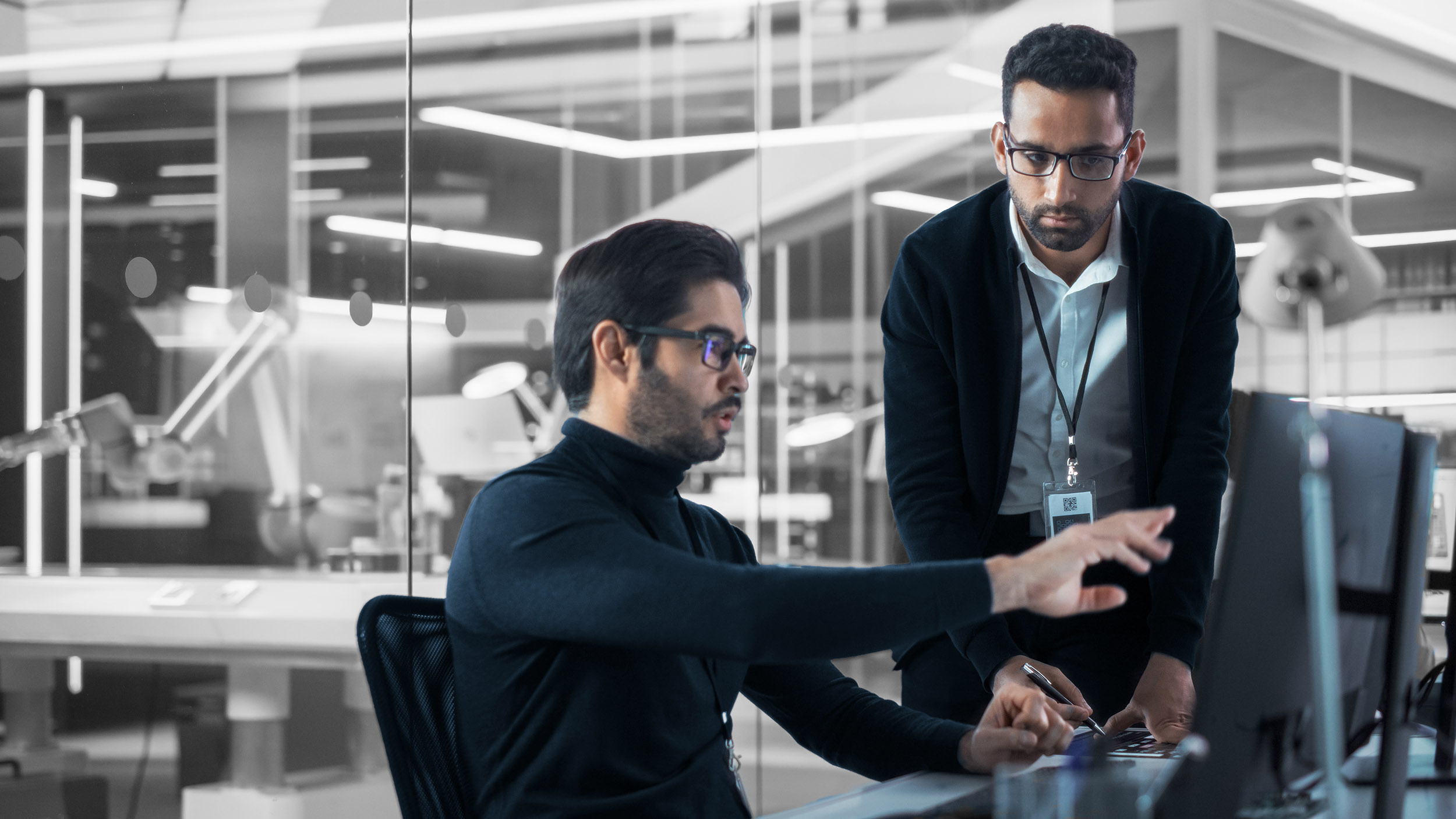 Two people standing over a desk talking