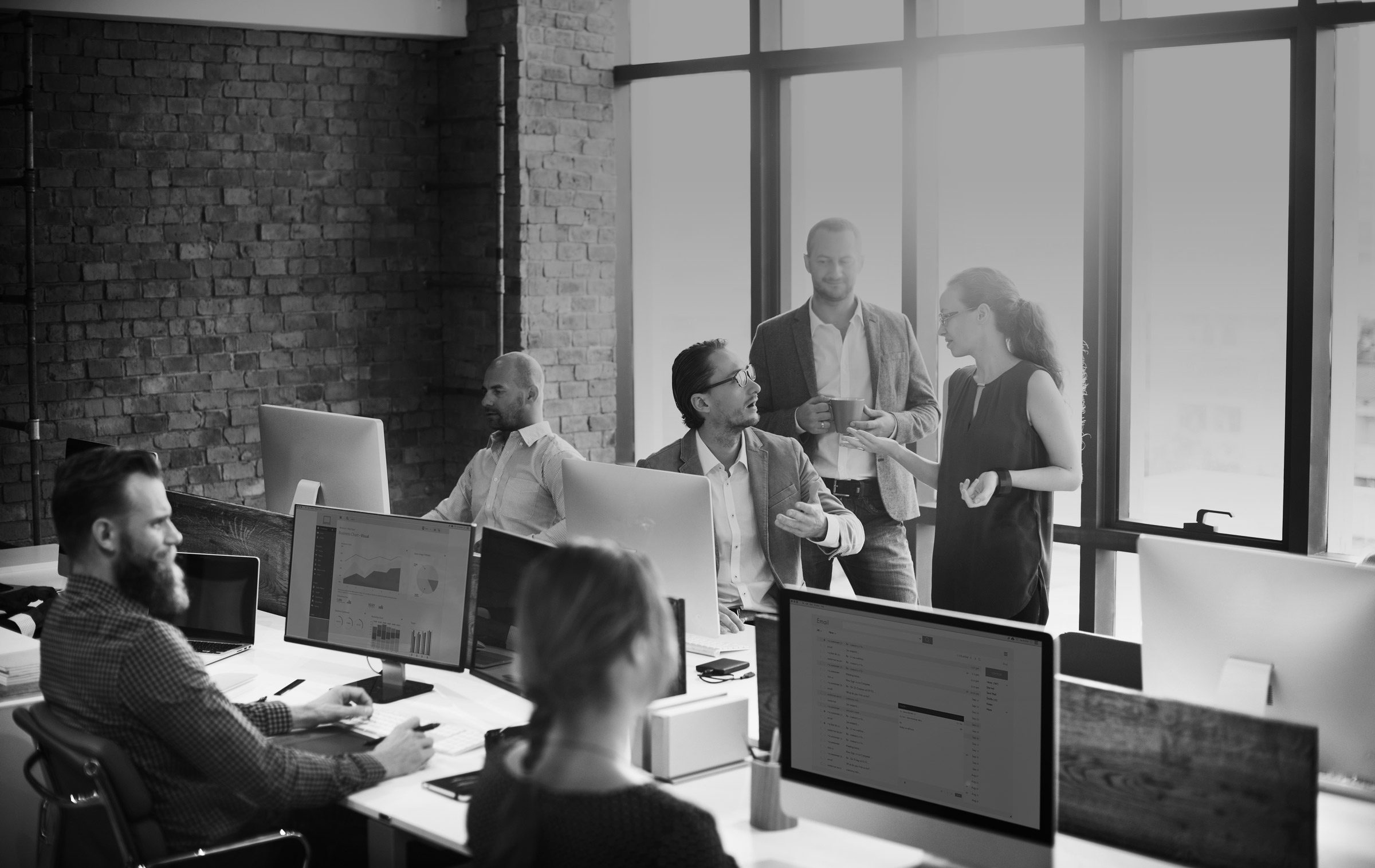 Group of six business finance professionals gather in office conference room surrounded by desktop computer to discuss financial close processes and reports