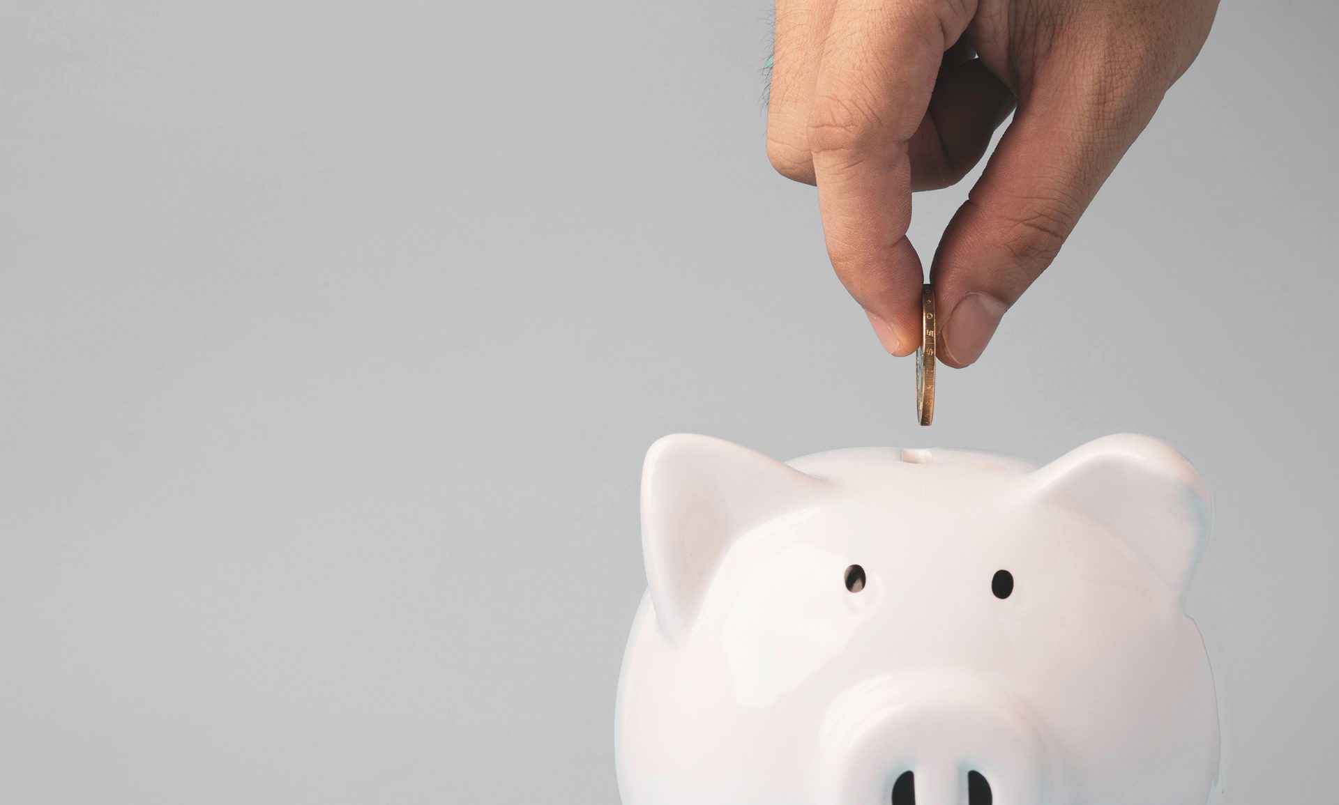 Coin being inserted into piggy bank