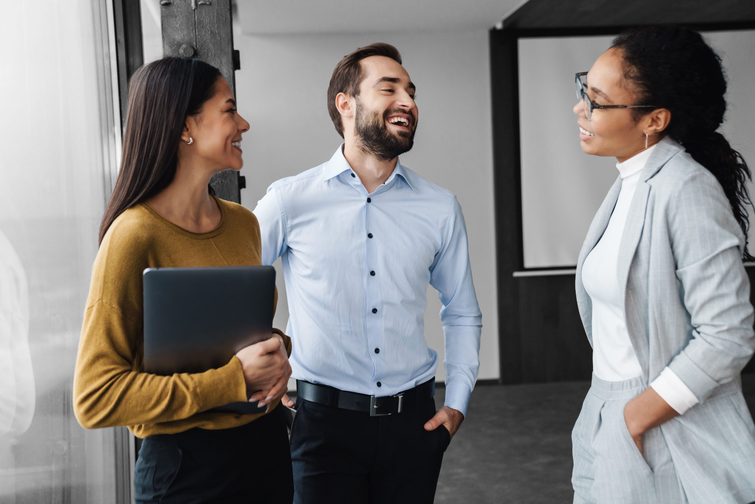 3 people standing having a conversation in a meeting room