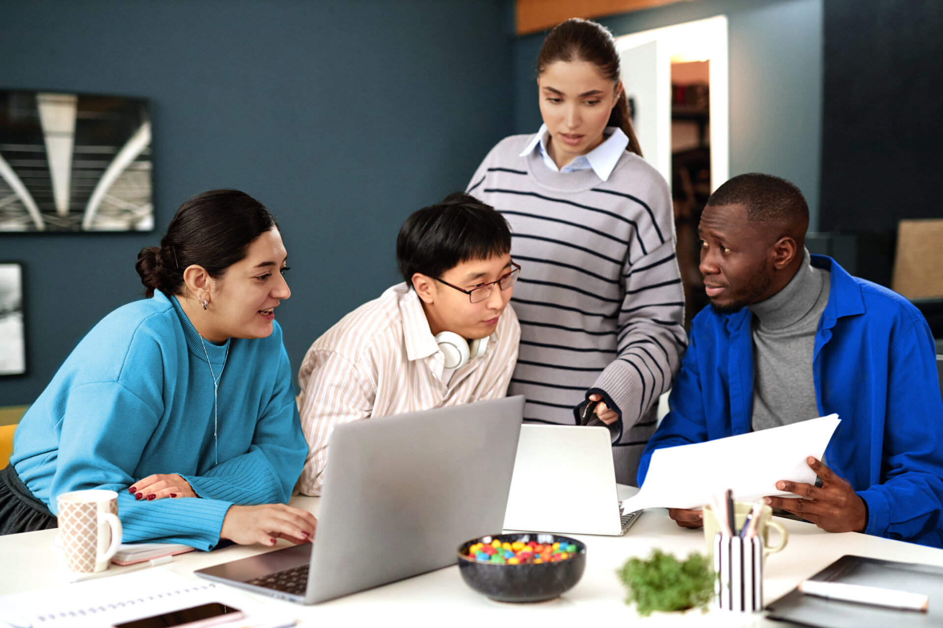 A diverse team collaborating effectively around laptops, illustrating productive teamwork enhanced by AI-driven financial close processes.