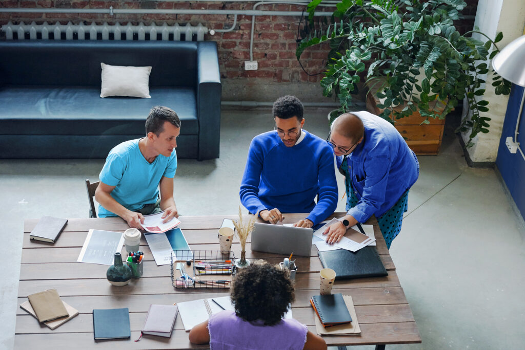 Overhead view of a team brainstorming around a laptop, exemplifying dynamic collaboration enhanced by AI-powered financial close solutions.